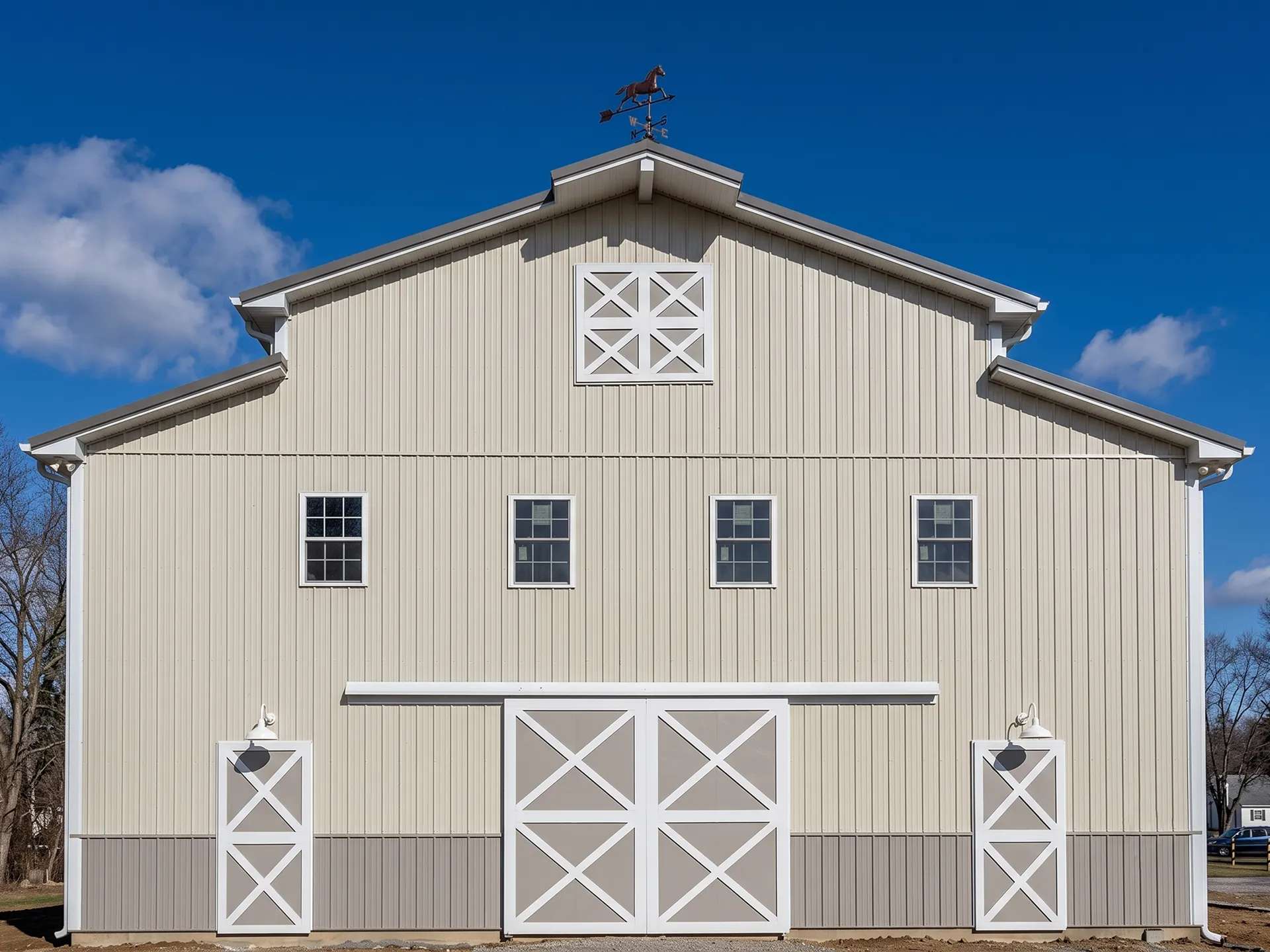 A beige barn with white trim features three windows, double doors, two side doors, and a rooster weather vane on the roof.