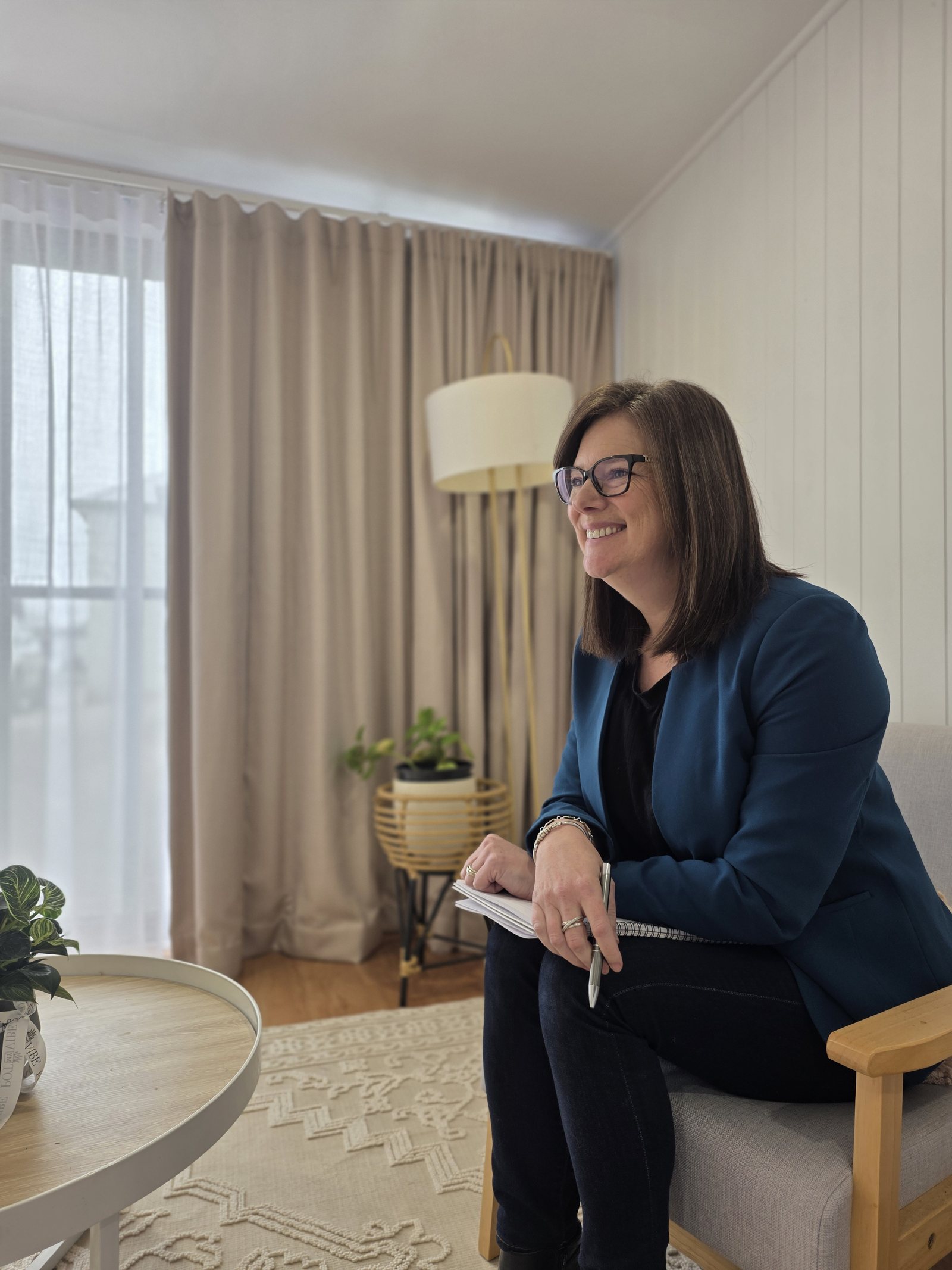A Spectrum team member in a blue blazer, notebook in hand, seated in the office lounge
