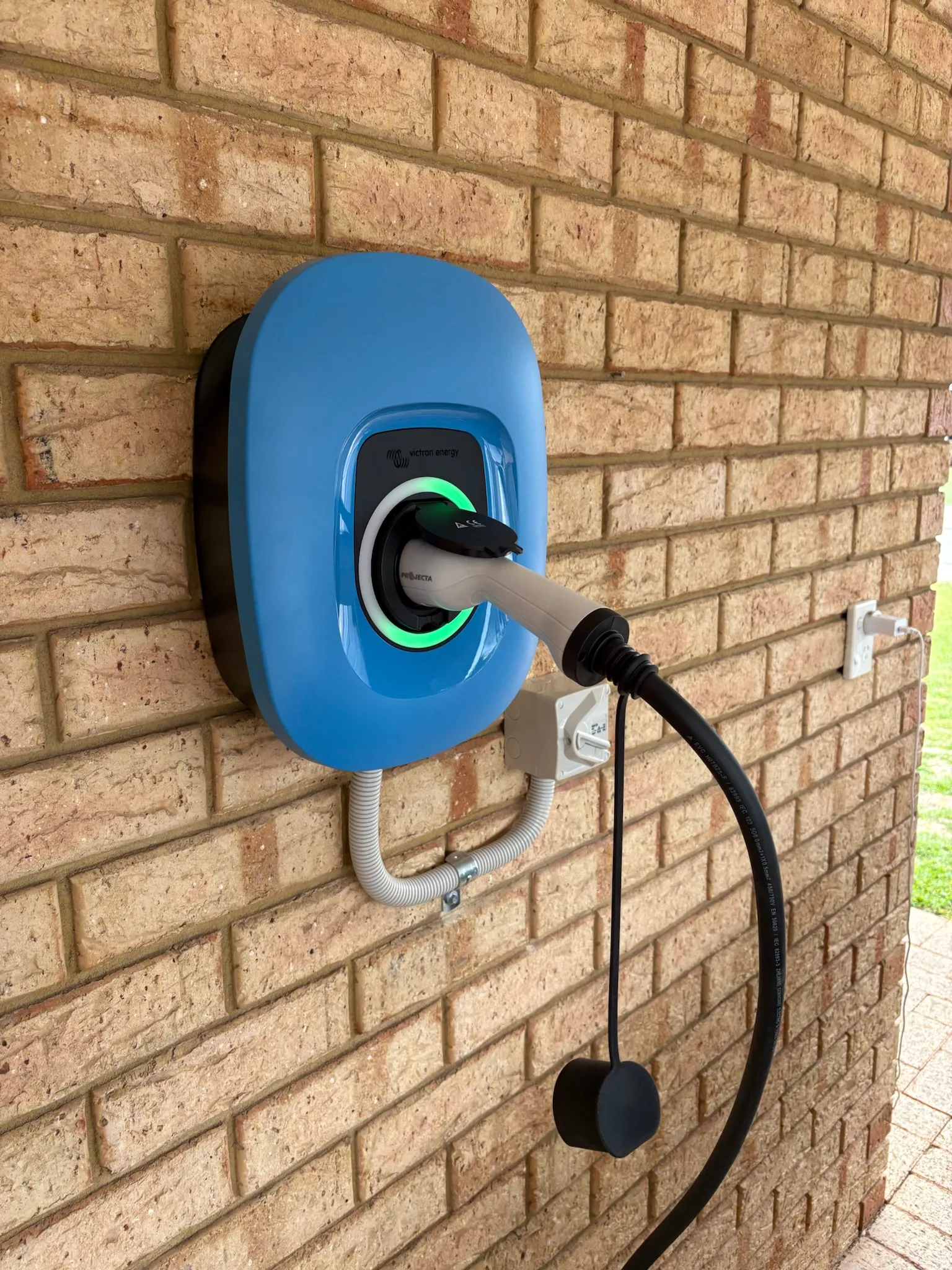 EV wall charger installed on a brick wall with the charging cable coiled
