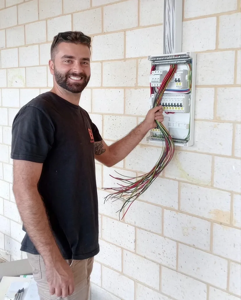 Buetec electrician fitting a wall light on a white brick wall