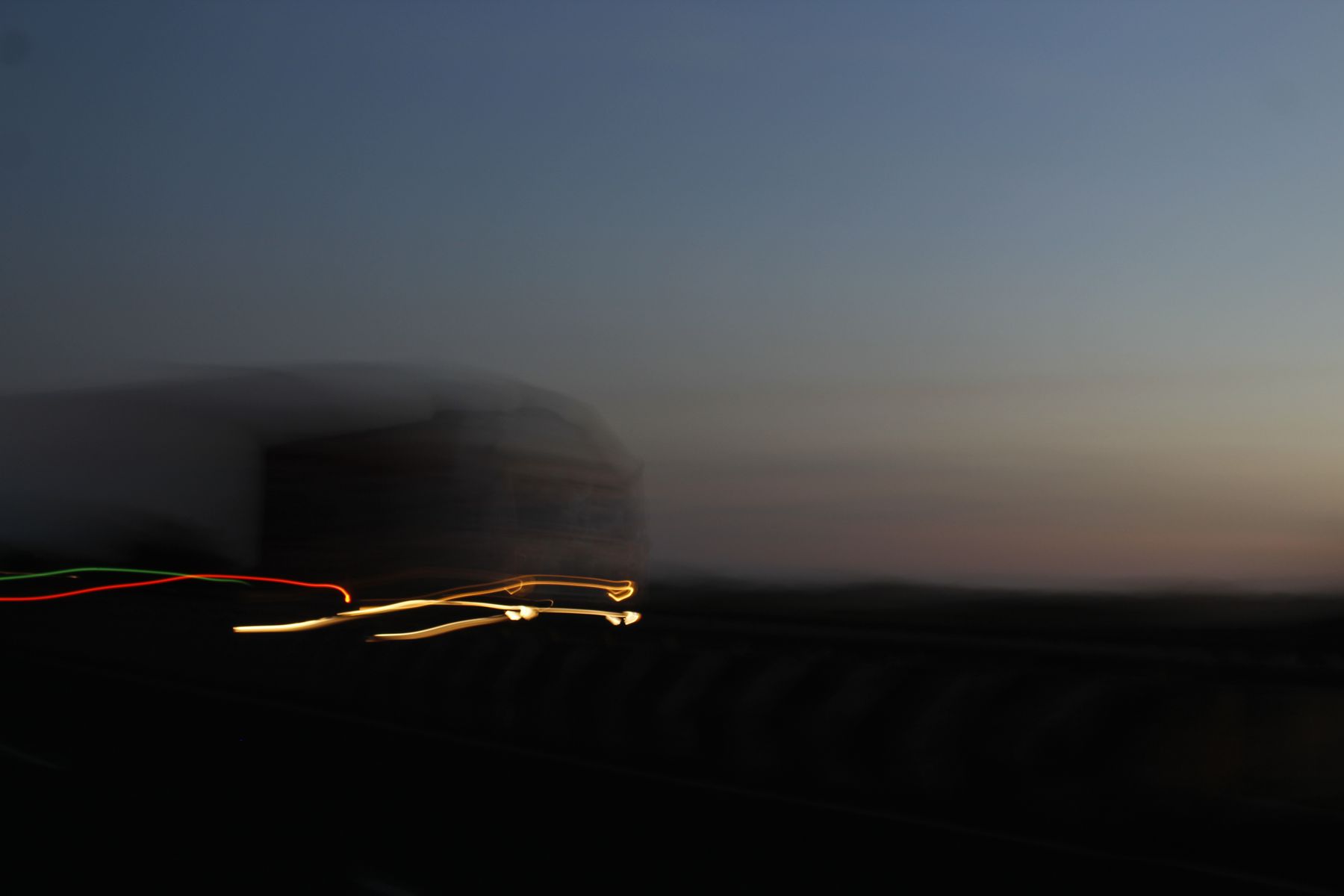 Traînées de phares au crépuscule le long d'une route