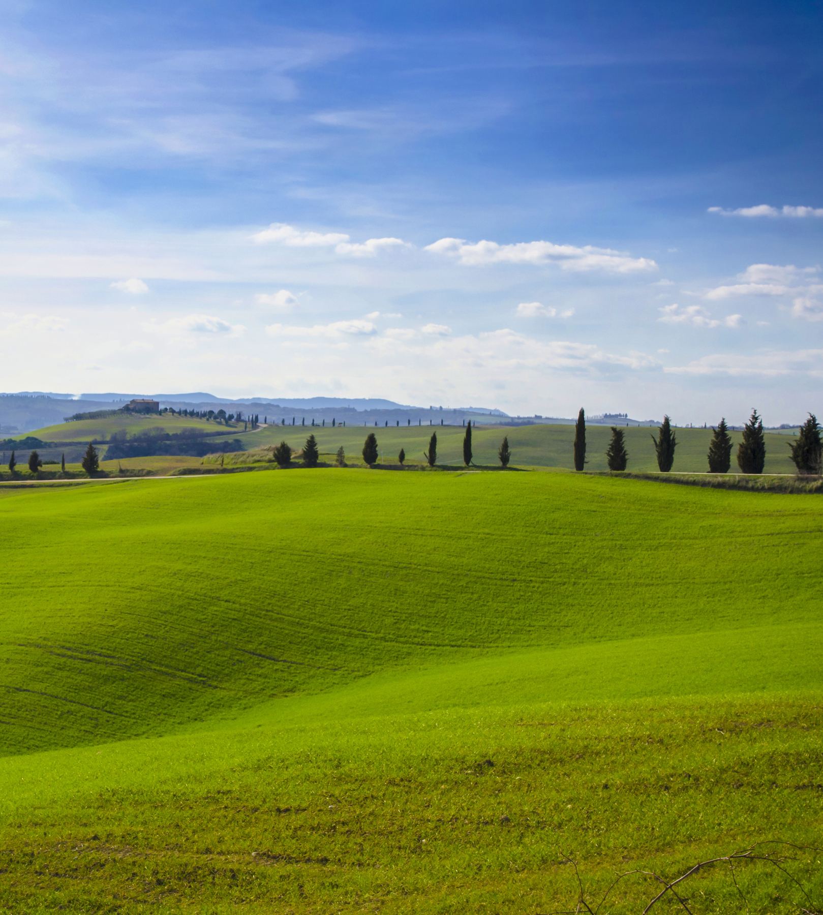 Route au pied de collines vertes, ciel bleu dégagé
