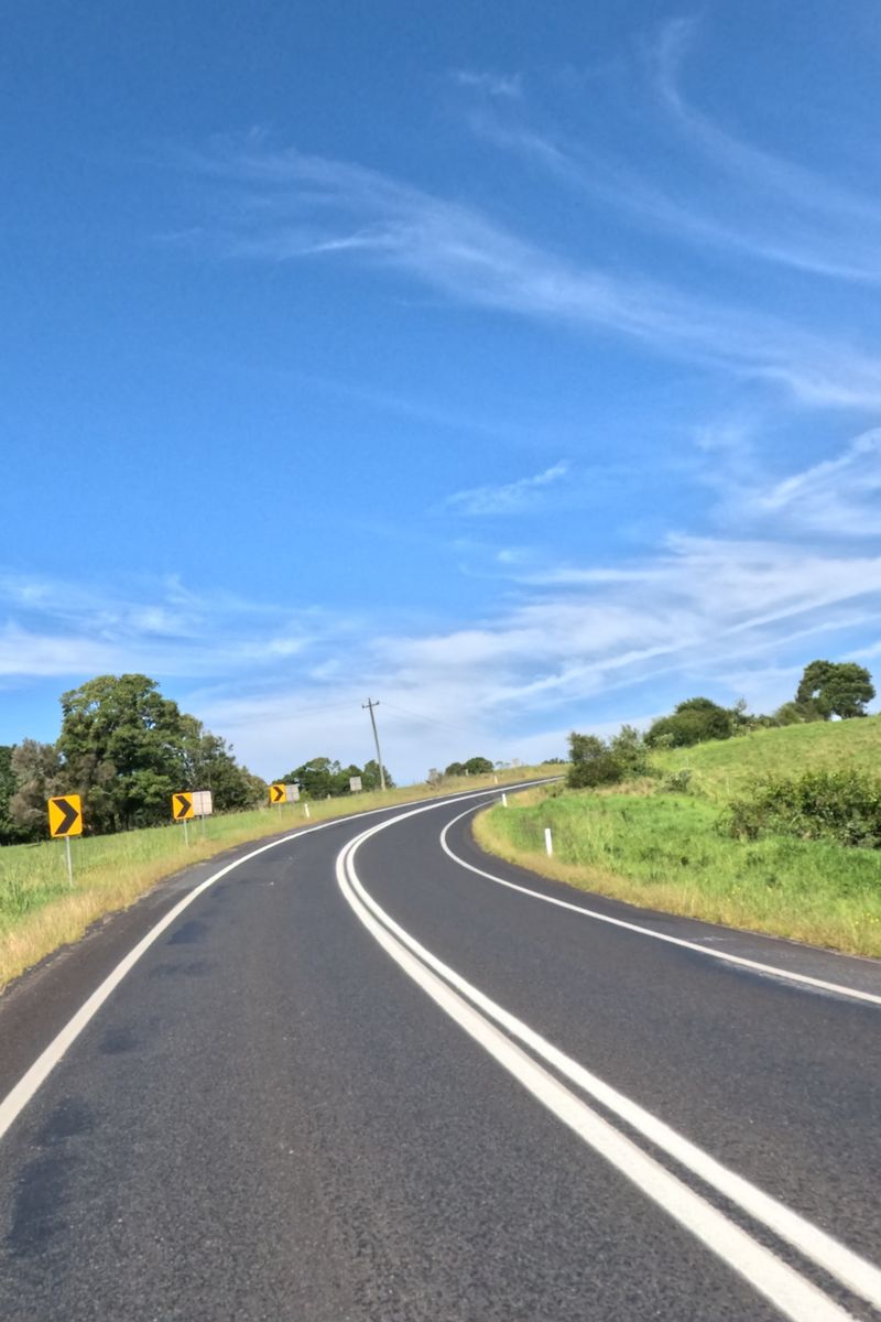 Route sinueuse entre des collines vertes sous un ciel bleu