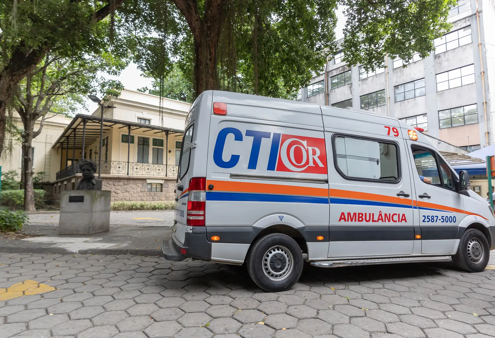 White ambulance van with CTI OR logo and phone number parked near a tree and buildings.