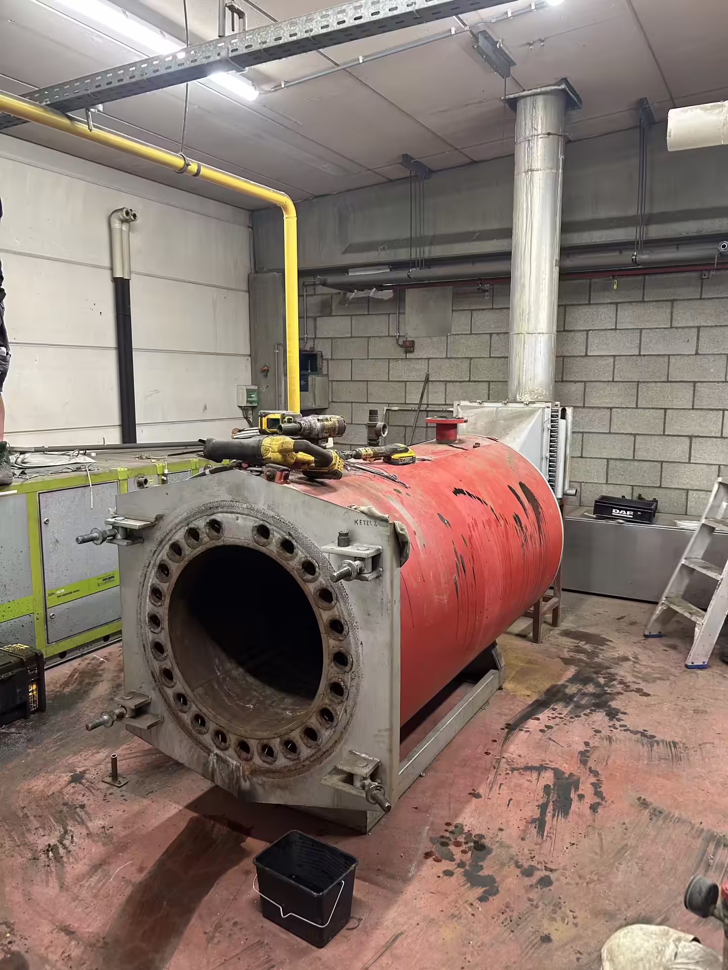 Rode industriële stookketel klaar voor demontage in een technische ruimte