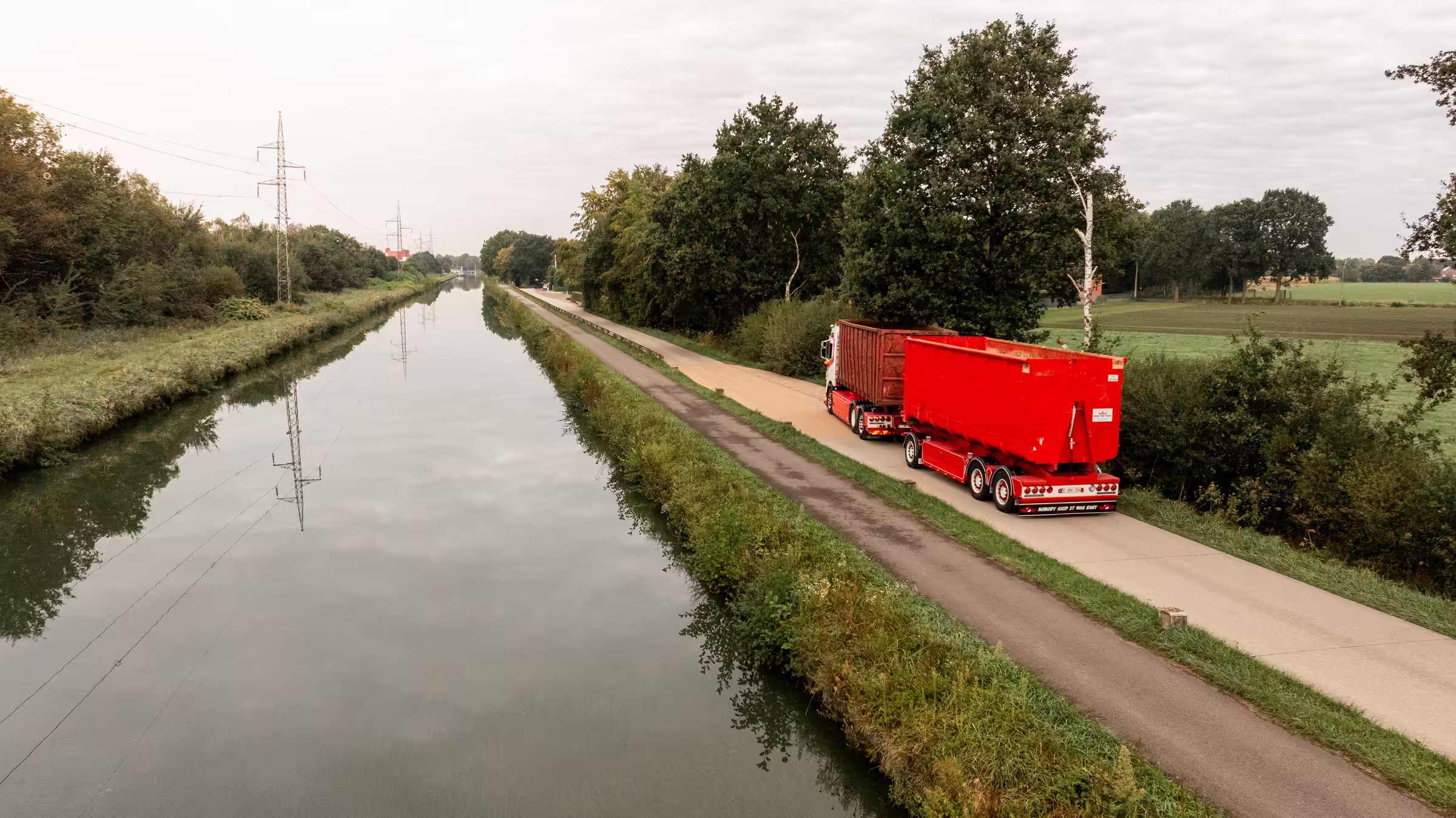 Rode Bob Peeters-vrachtwagen met containers langs de vaart in Sint-Lenaarts