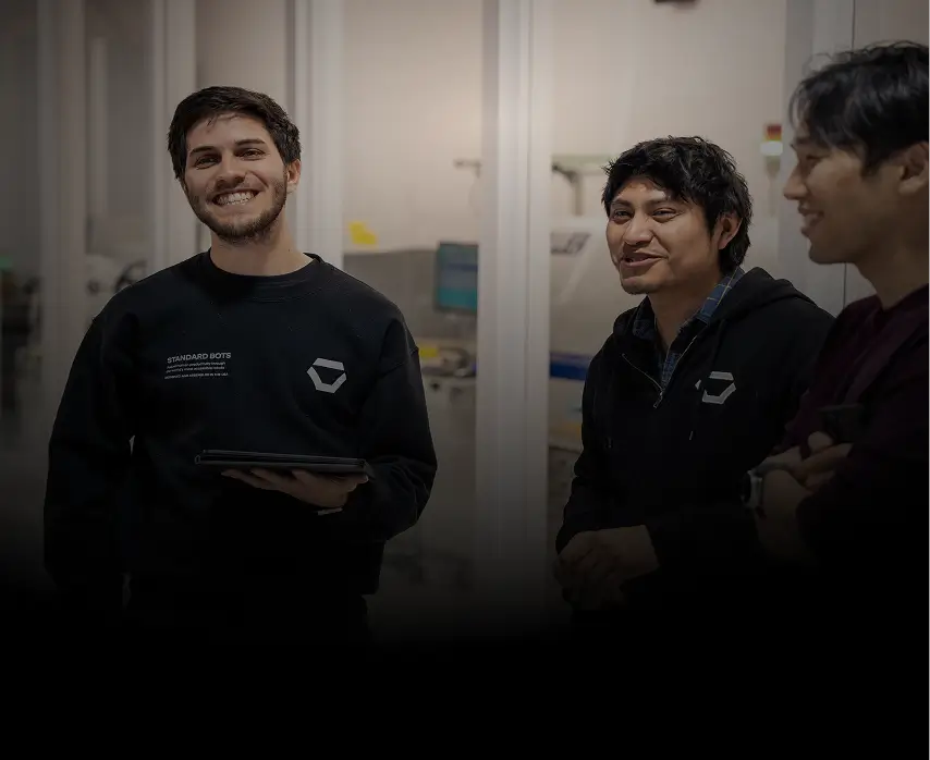 Smiling Standard Bots team members in the company lab