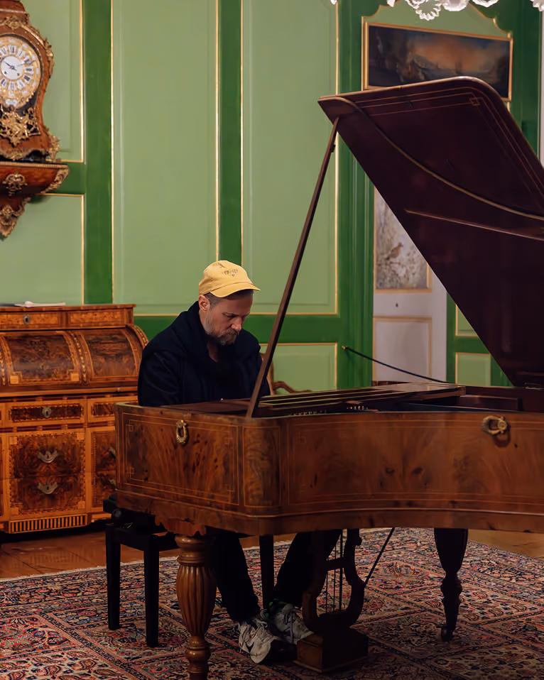 Pianiste jouant sur un piano à queue ancien dans un salon aux boiseries vertes