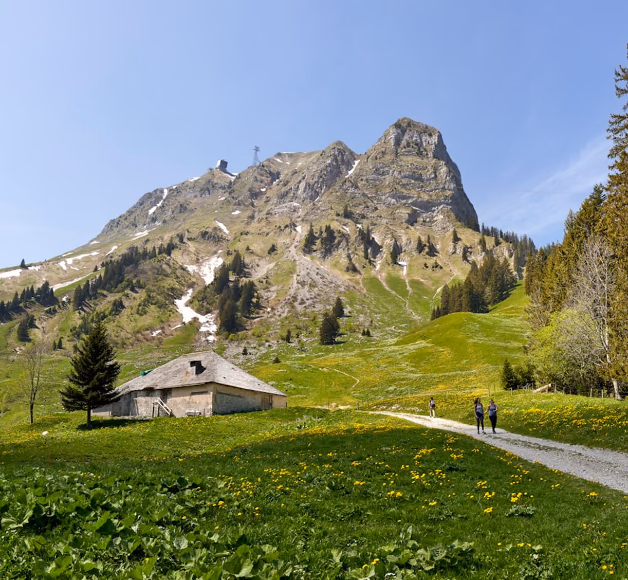 Chalet d’alpage et randonneurs au pied d’un sommet rocheux des Préalpes