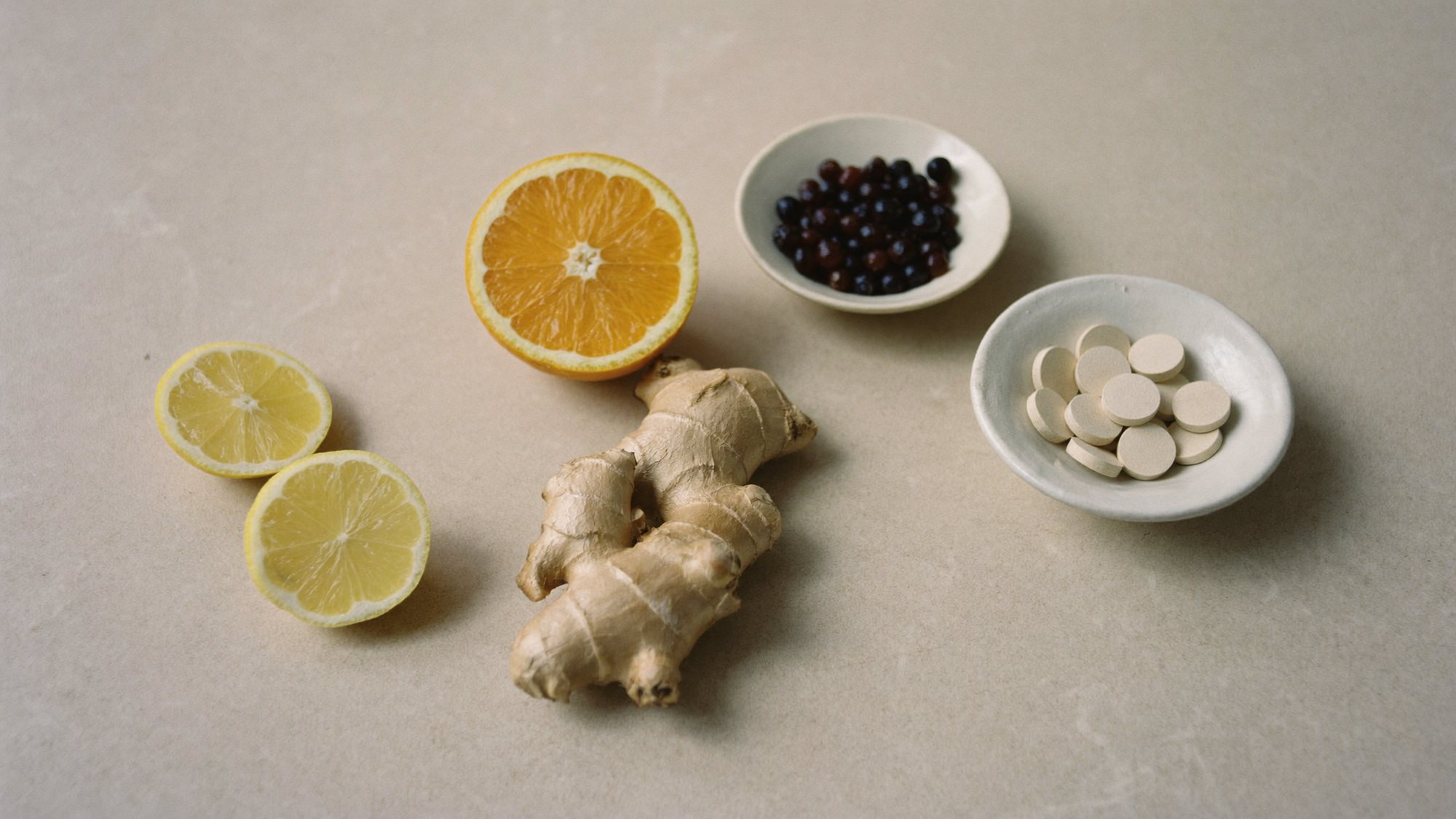 Orange, lemon, ginger root, elderberries and white tablets on a stone counter
