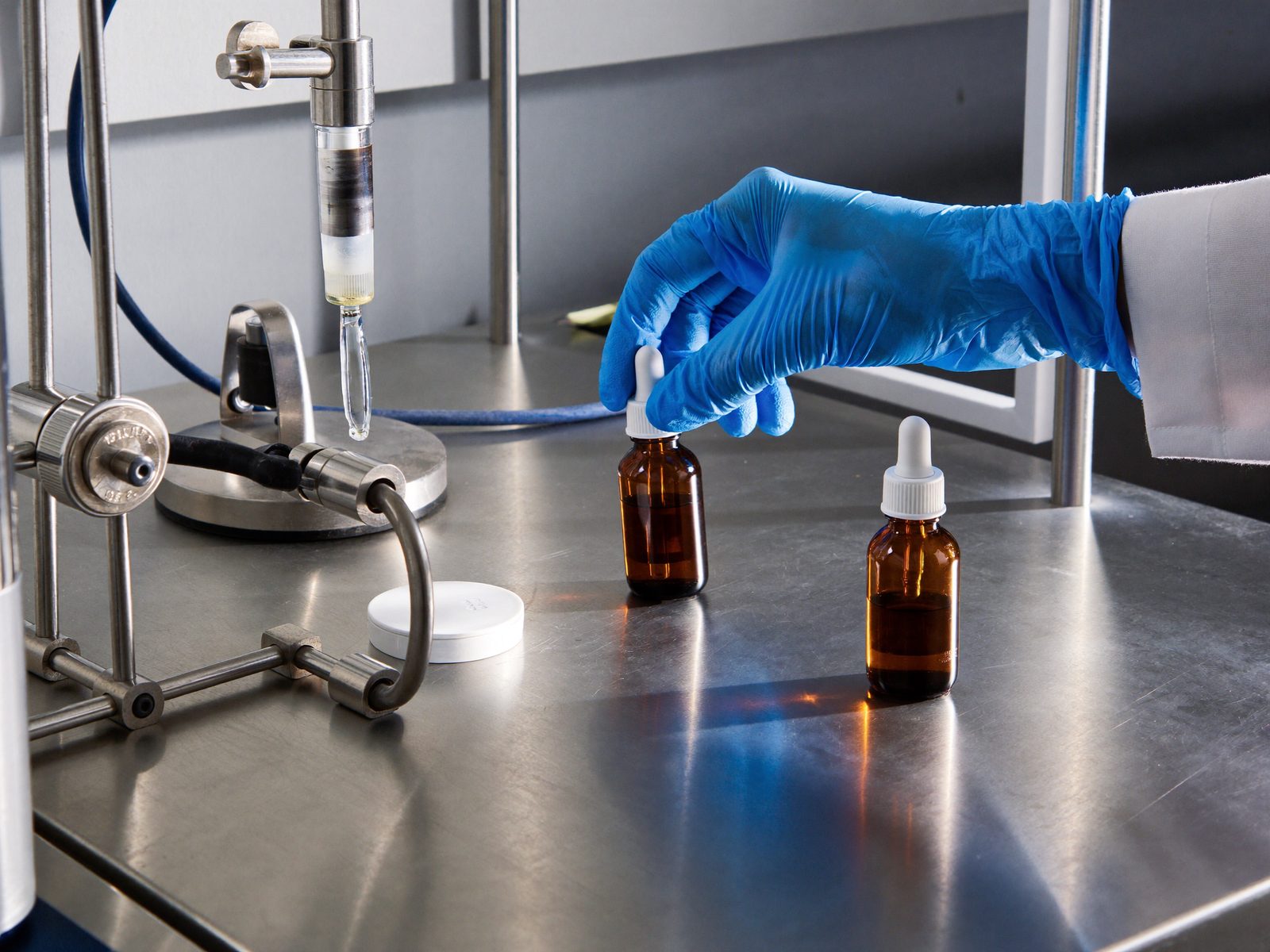 Gloved hand placing amber dropper bottles on a filling line
