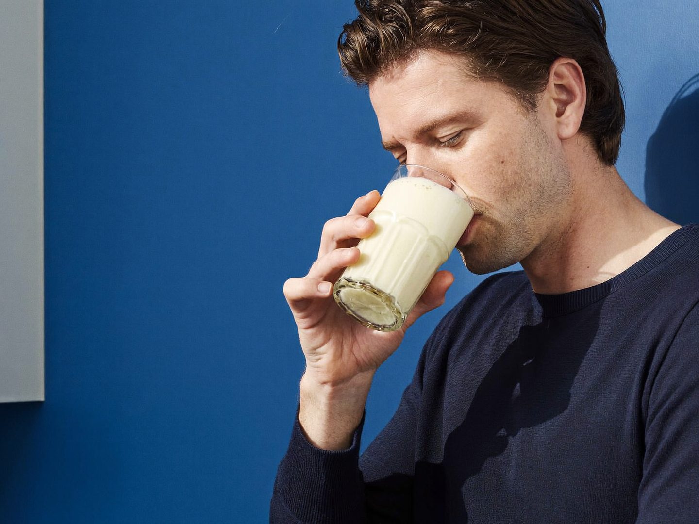 Man drinking a vanilla protein shake from a glass