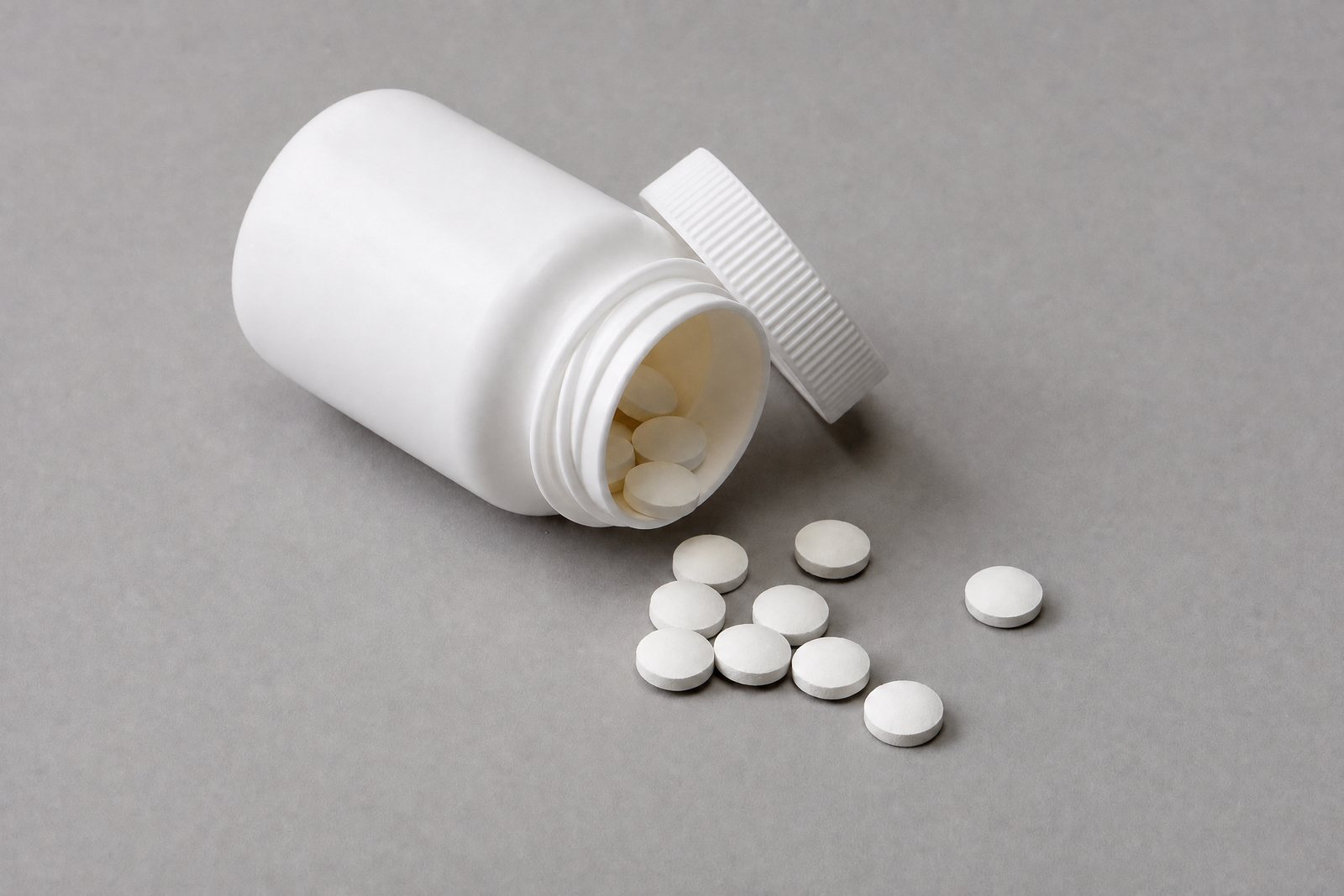 White tablets spilling from an unlabeled bottle