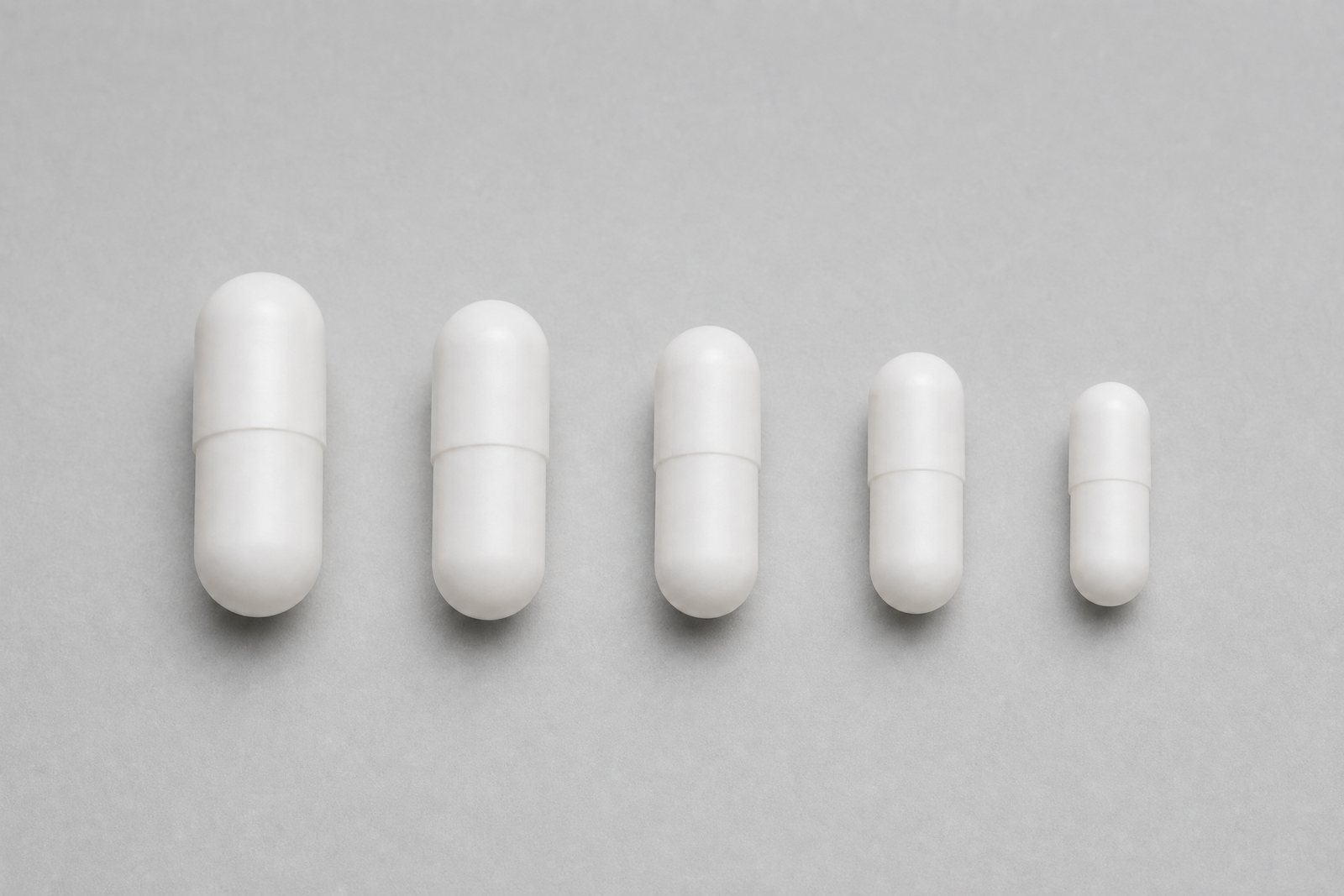Empty white capsules in sizes 000, 00EL, 00, 0 and 1 side by side
