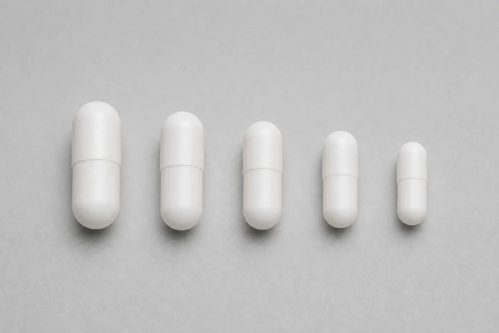 Empty white capsules in sizes 000, 00EL, 00, 0 and 1 side by side