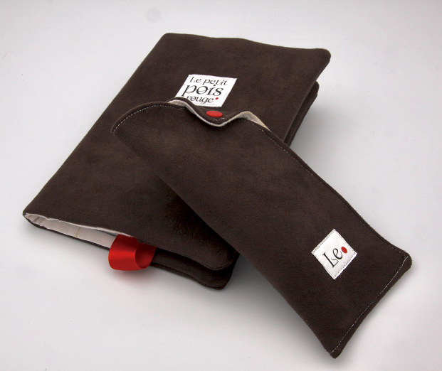 Two dark brown suede fabric cases, one larger and folded and one smaller with a flap closure, each with white labels featuring red dots and text reading 'le petit pois rouge' and 'Le.'