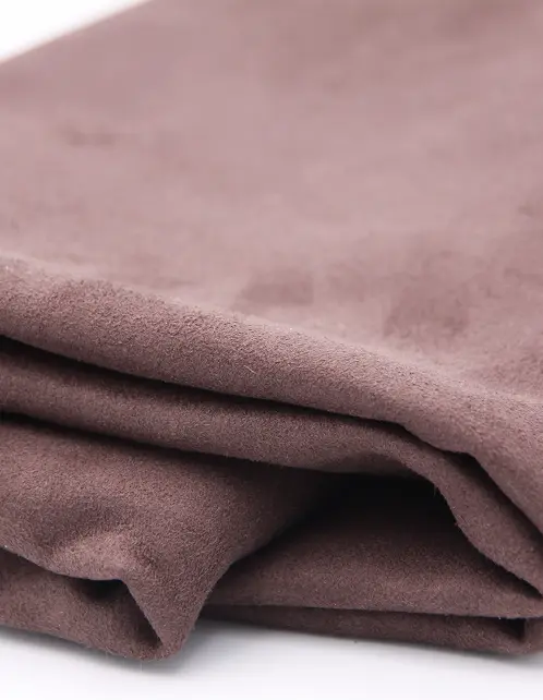Close-up of folded brown suede fabric with a soft texture on a white surface.
