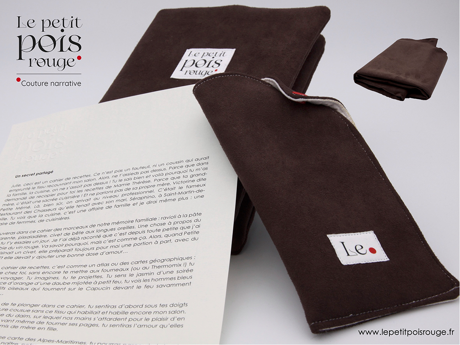 Brown fabric item, possibly a folded pouch or book cover, with a white label that reads 'Le petit pois rouge' in black and red text, alongside an open book showing French text. The fabric appears soft and suede-like, and another folded piece of the same material is visible in the top right corner. The background is plain white with the logo 'Le petit pois rouge Couture narrative' on the left side.