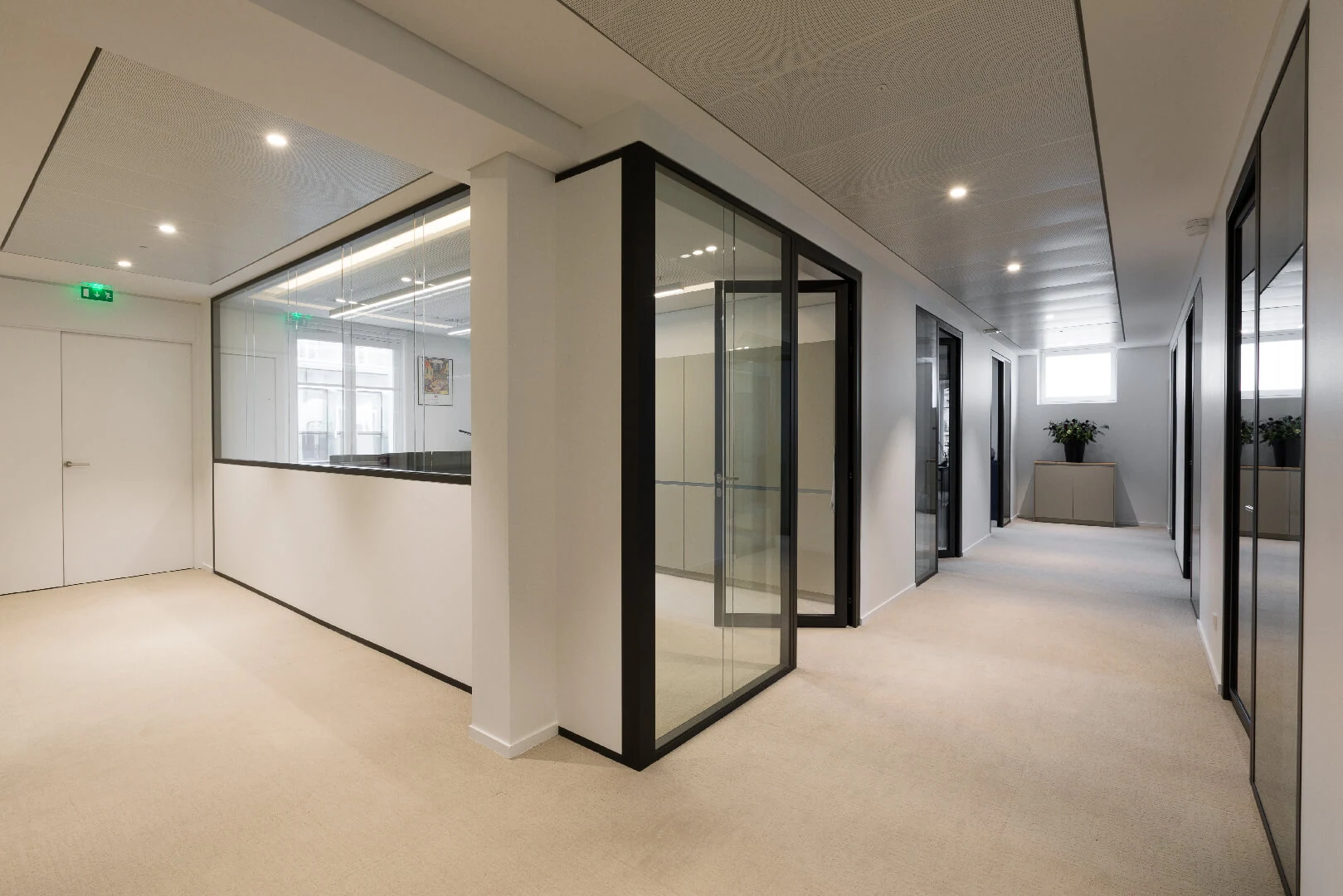 Office corridor with black-framed glass partitions and beige carpet
