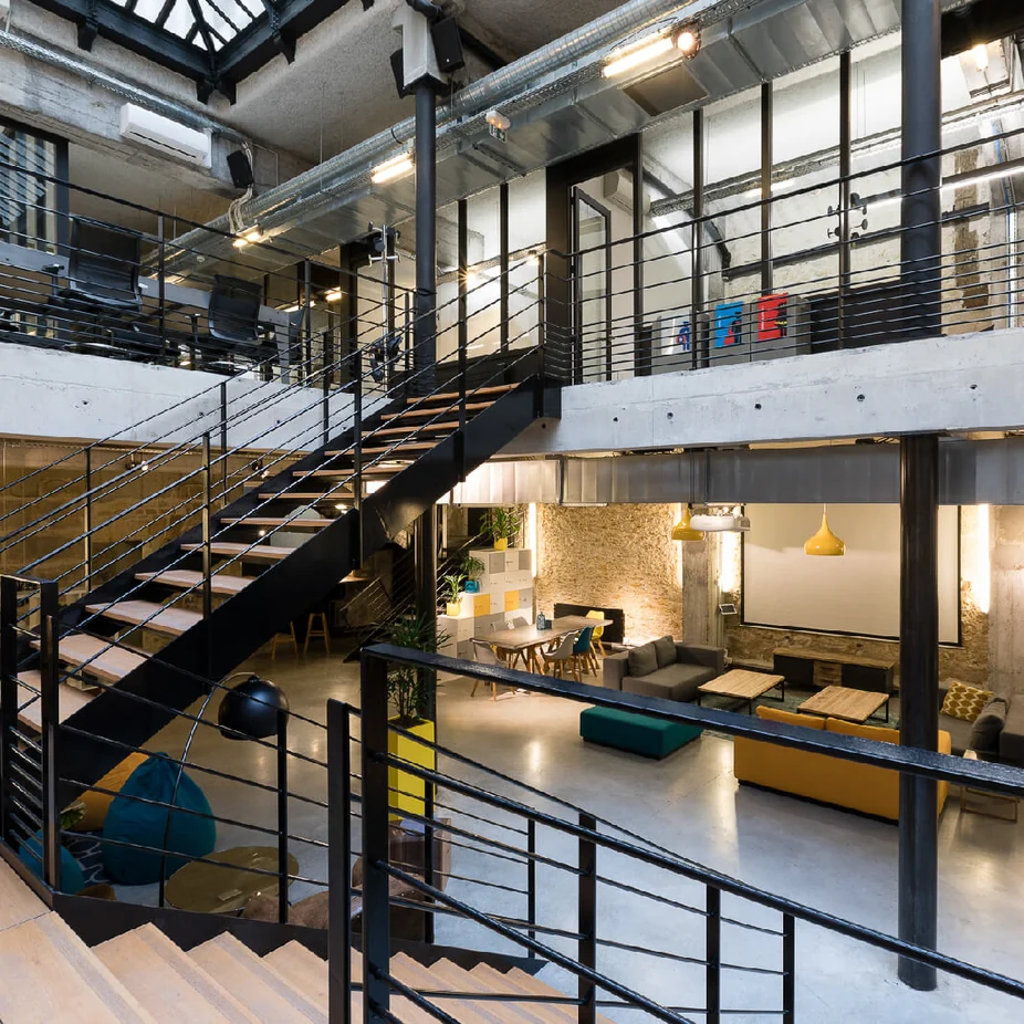 Industrial-style office atrium with black steel staircase and mezzanine