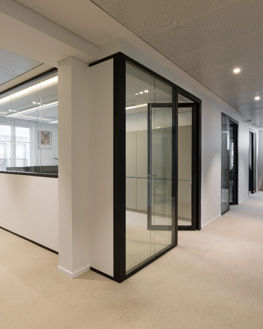 Office corridor with black-framed glass partitions and beige carpet