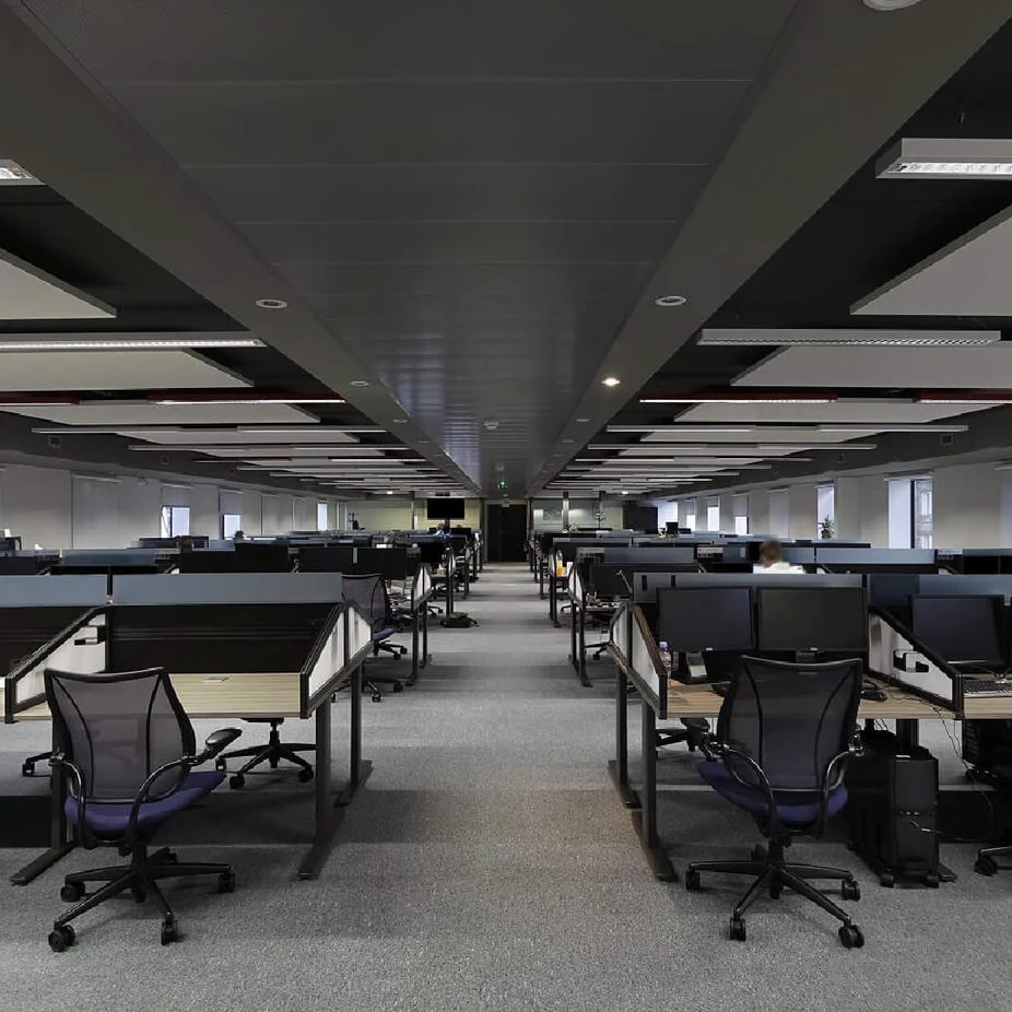 Large open-plan office with rows of workstations under a dark ceiling
