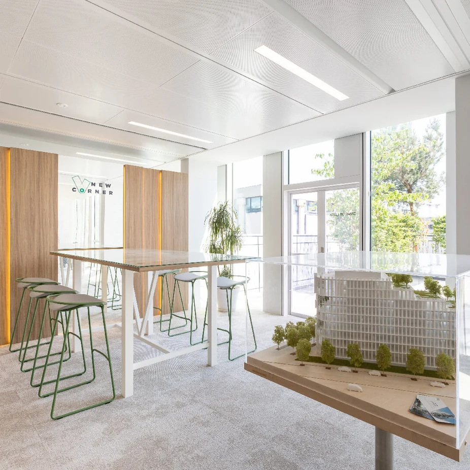 Showroom area with high table, green stools and an architectural building model