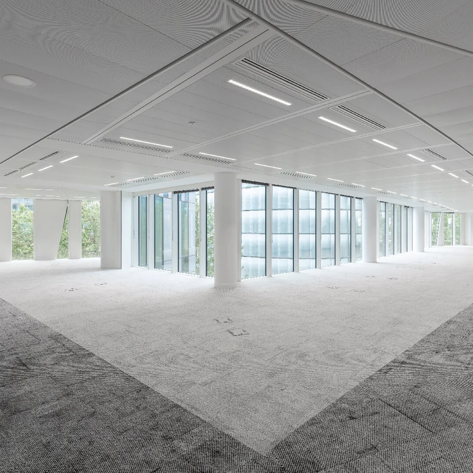 Vacant curved office floor with patterned grey carpet and linear ceiling lights