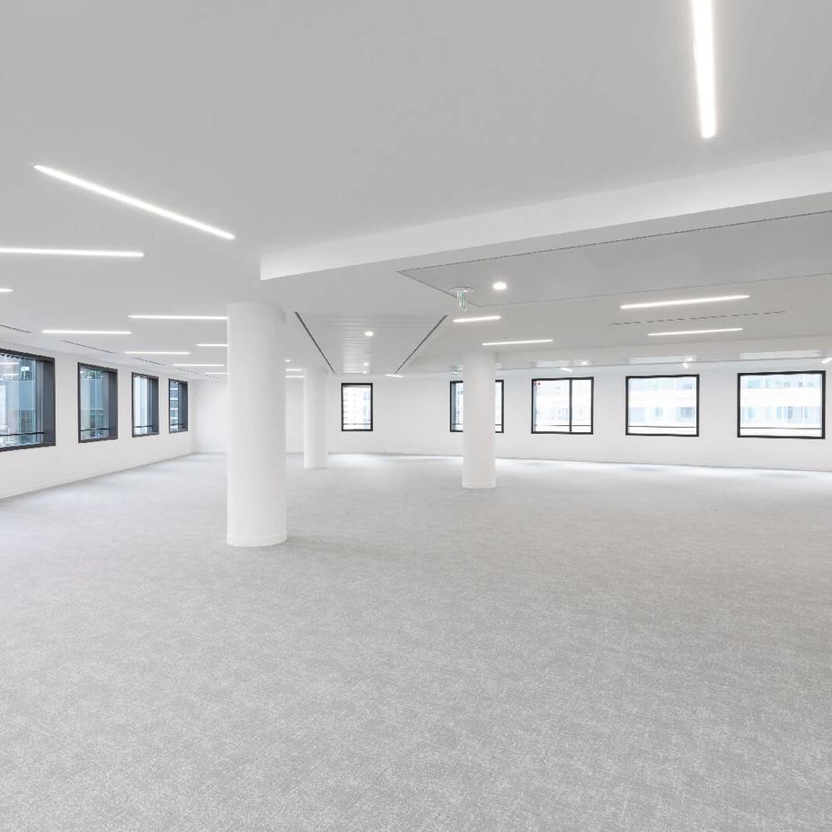 Empty white office floor with round columns and small square windows