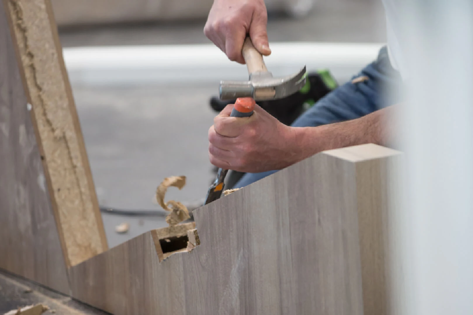 Carpenter hammering a fitting into a wood laminate panel
