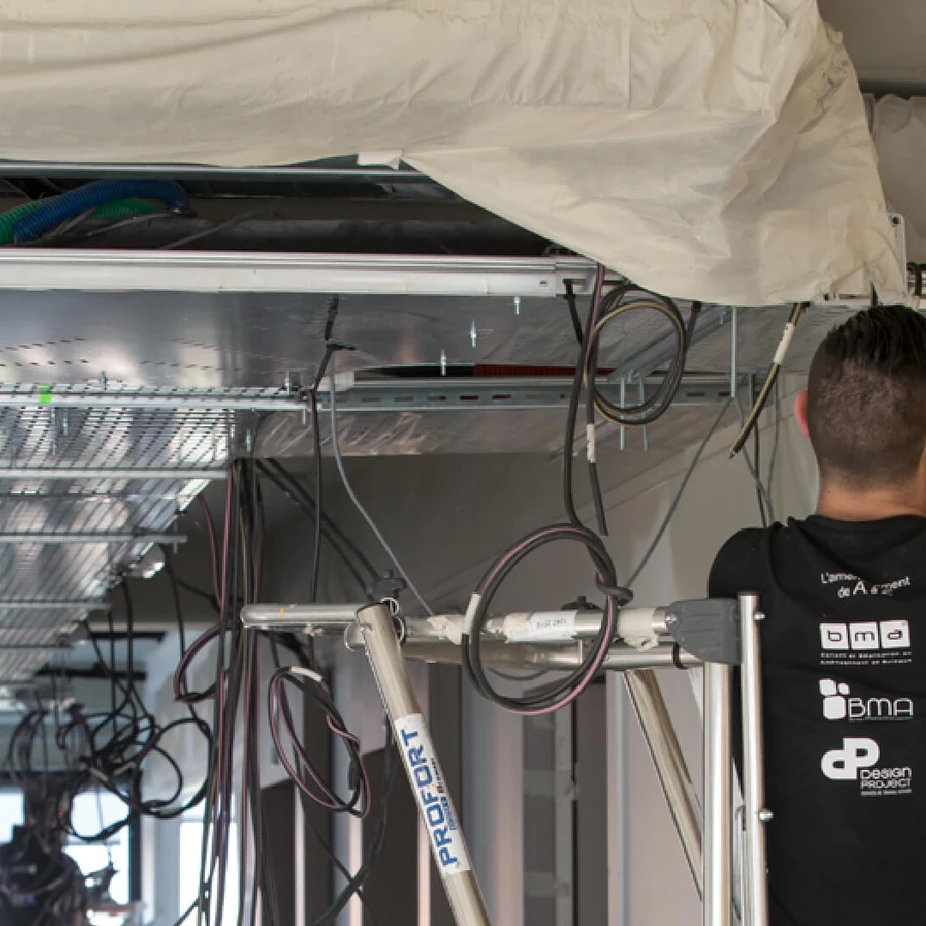Technician installing cables in an open office ceiling