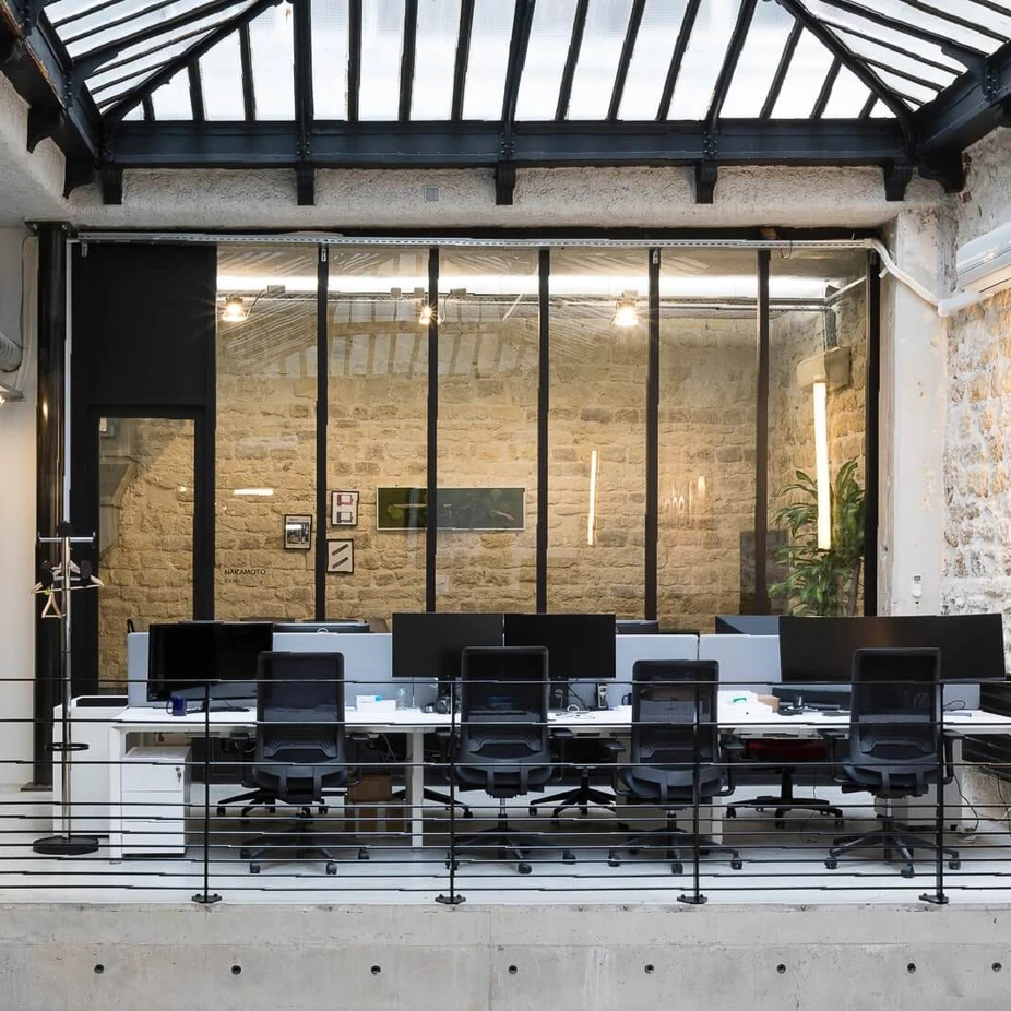 Workstations under a glass roof in a converted building with stone walls