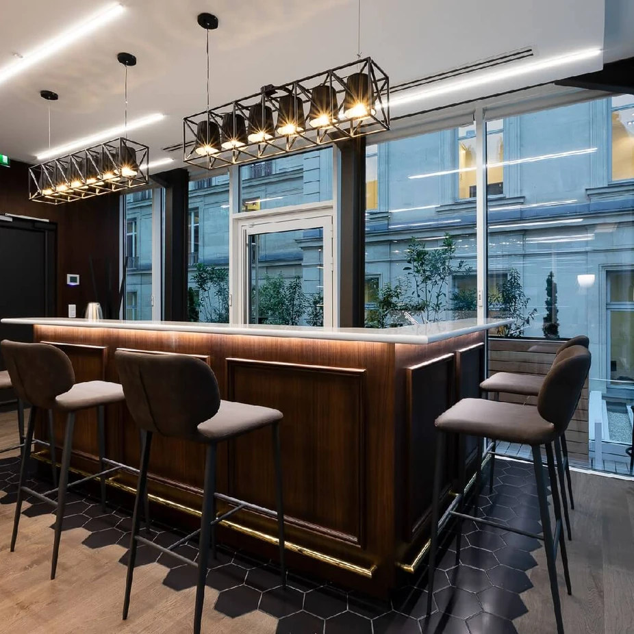 Dark wood bar with stools and black cage pendant lights by large windows