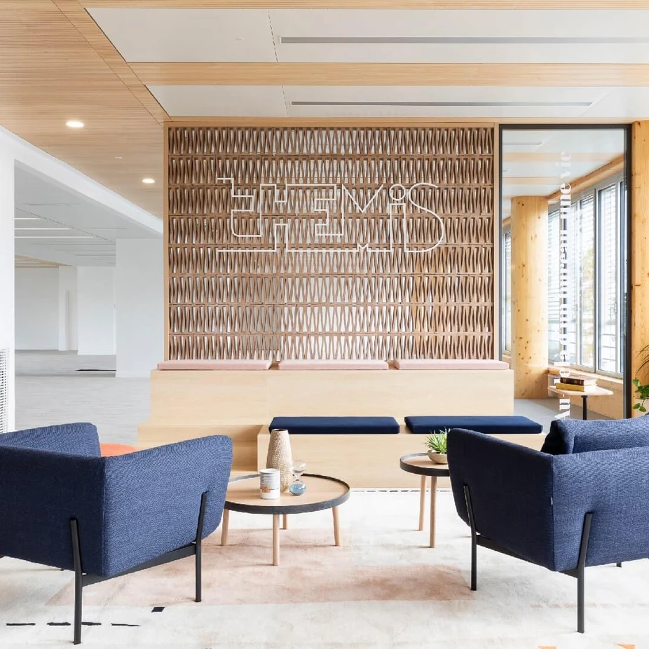 Reception lounge with navy armchairs in front of a decorative wooden screen wall