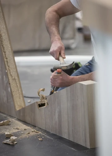 Craftsman chiselling a wooden panel by hand during fit-out works