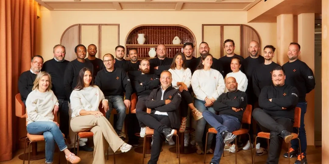 BMA team gathered for a group photo in a warm-toned lounge with arched shelves