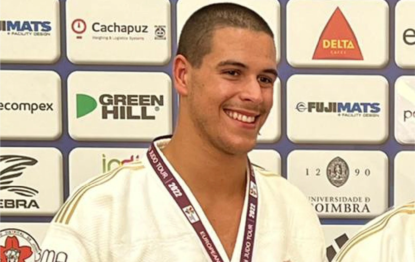 Smiling judoka in a white judogi wearing a medal, sponsored by BMA Group