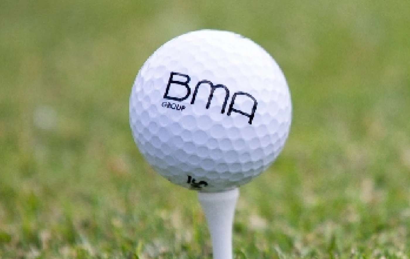 Golf ball with the BMA logo on a tee in the grass