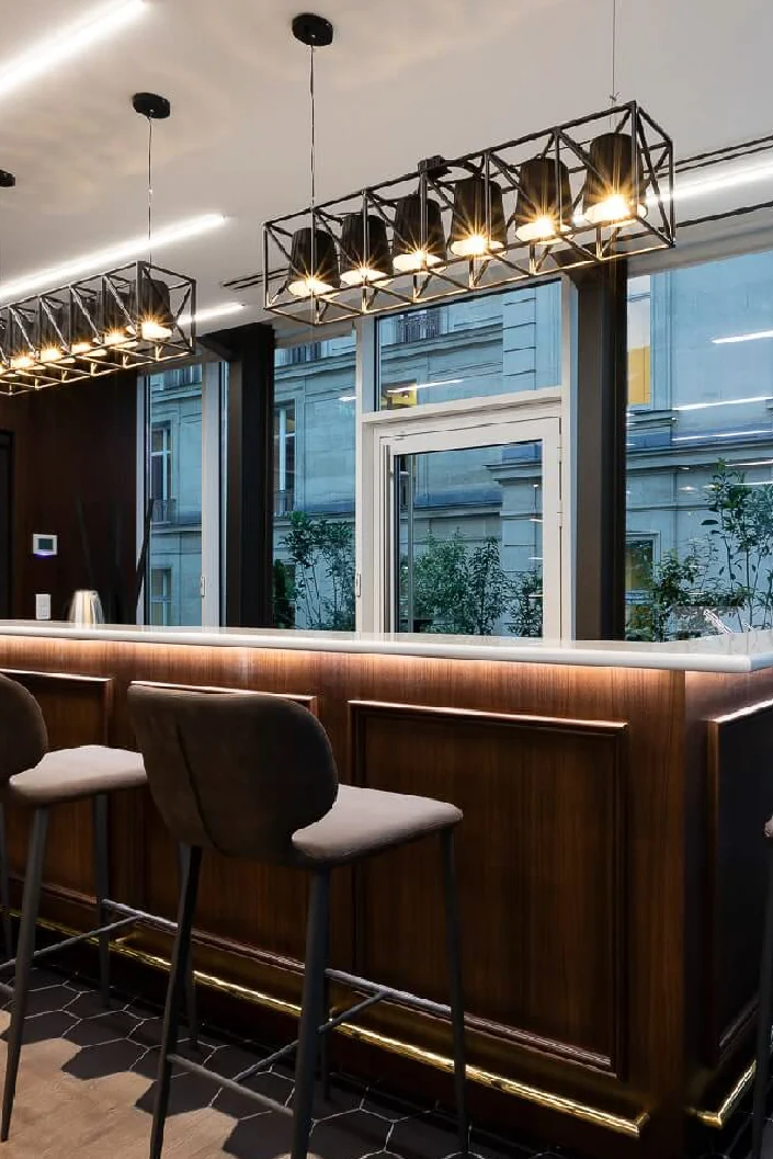 Dark wood office bar with high stools under black geometric pendant lights