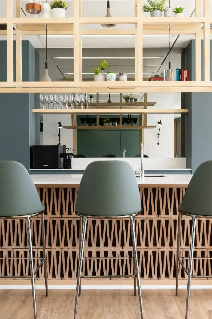 Kitchen counter with green bar stools and a suspended wooden shelf with plants