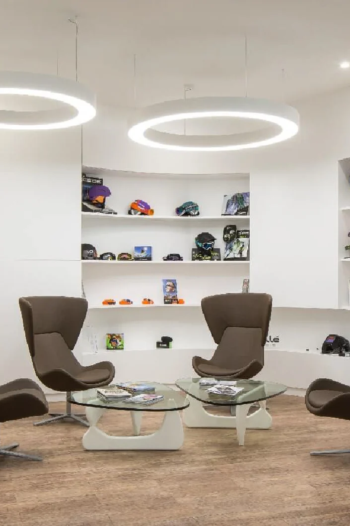Showroom lounge with brown swivel armchairs, ring lights and white display shelves