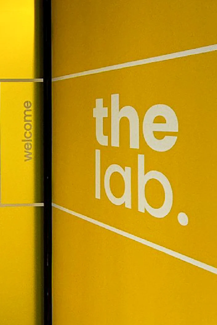 Yellow wall with white "the lab." lettering next to a black-framed door