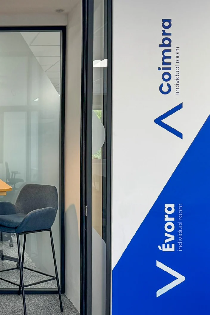 Blue and white room signage reading Coimbra and Evora beside glazed meeting rooms