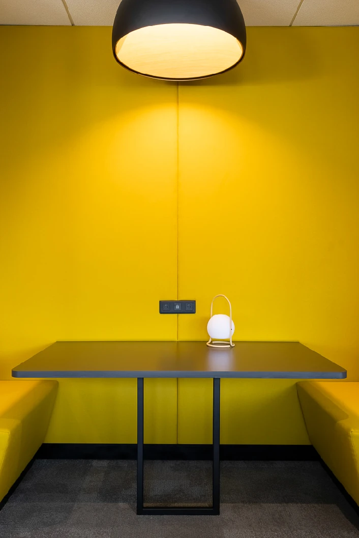 Yellow upholstered meeting booth with table and pendant lamp