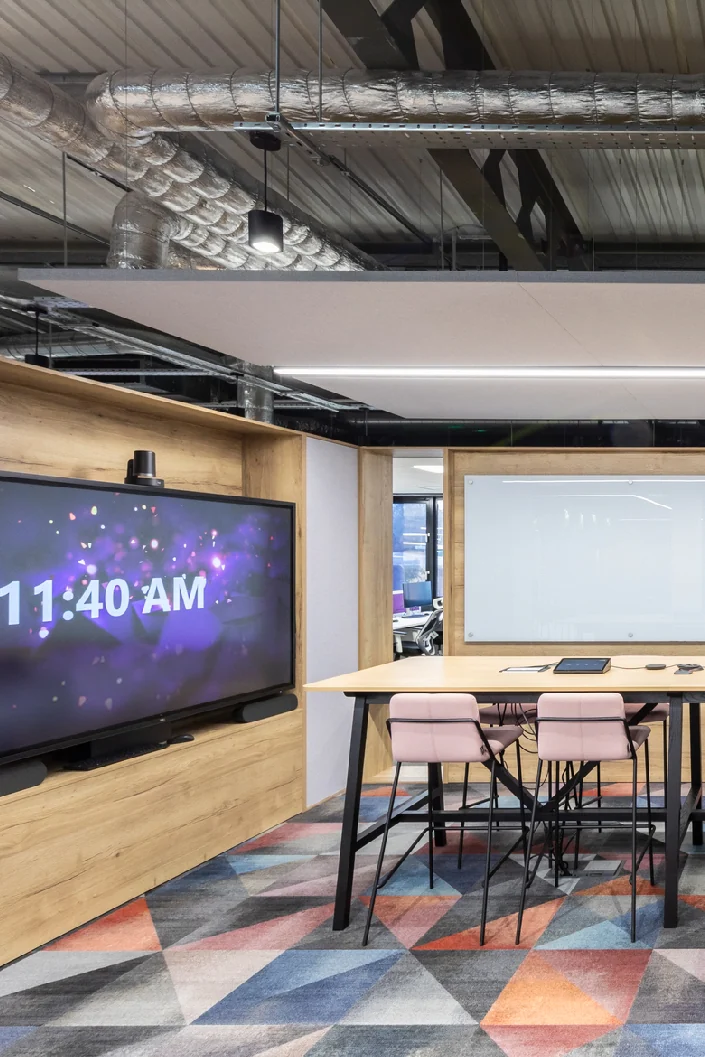 Collaborative area with a large wall-mounted display and a high meeting table