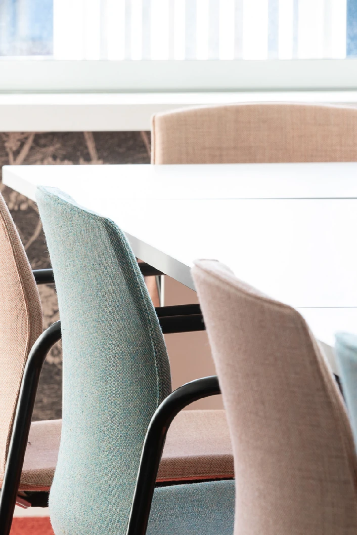 Pastel pink and green upholstered chairs around a white meeting table