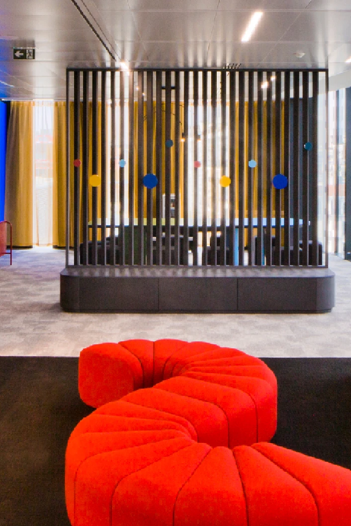 Colourful breakout area with red modular sofa and slatted wooden screen