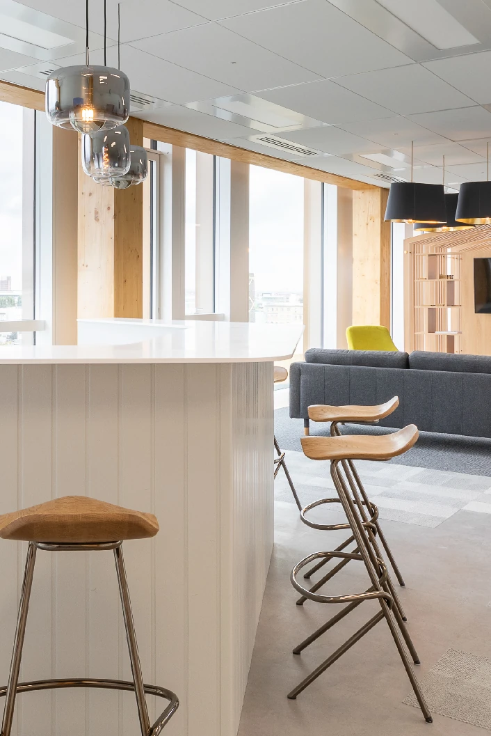 Office kitchen island with bar stools next to a lounge area