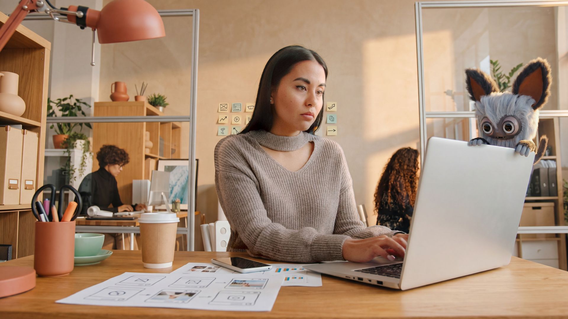 Marketing lead reading a discussion thread on a laptop in a warm SaaS office, a Cluma monster peeking over the lid