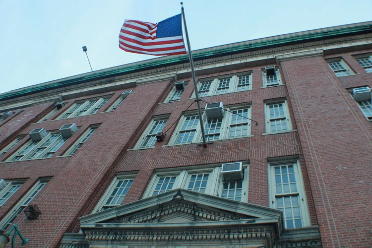American flag flying over a large brick school building